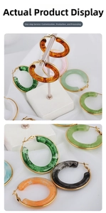 Detailed macro view of resin hoop earrings with assorted marble patterns and gold metal bases