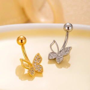 Macro detail of gold and silver butterfly navel rings with sparkling crystal wings