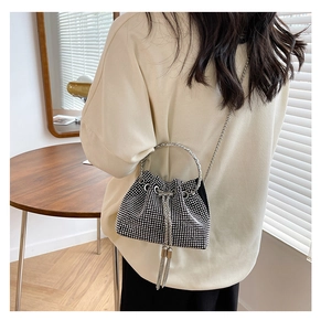 Detail of black rhinestone bucket bag with metal ring handle and chain fringe tassels