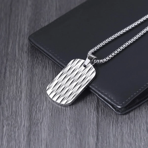Silver stainless steel dog tag necklace with wave texture on a black leather wallet