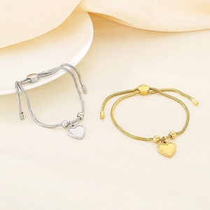 Detailed shot of gold and silver snake bone chain bracelets with heart charms and sliders