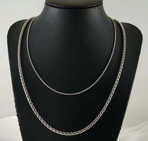 Detailed close-up of layered stainless steel necklaces with thin and thick silver chains