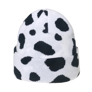 Winter knitted beanie featuring black and white cow print patterns on soft fabric