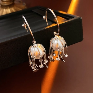 Gros plan de boucles d'oreilles C argentées avec perles et glands d'étoiles sur plateau