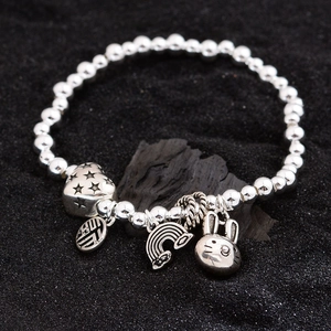 Silver beaded bracelet with rabbit, heart and lucky character charms on black background