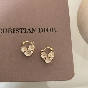 Macro shot of gold plated flower earrings with cubic zirconia on textured display