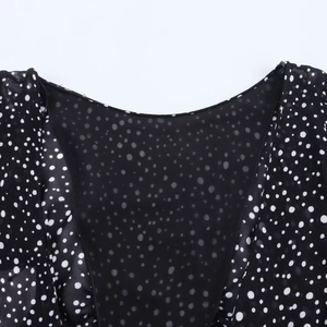 Close-up of V-neckline on a black polka dot chiffon dress with flared ruffle sleeves