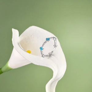 Detail of silver clover ring with blue stones and crystals on white flowers