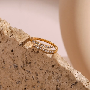 Detailed view of a gold-plated criss-cross ring with zircon on a natural stone surface