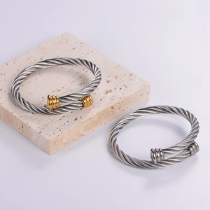Detail of twisted wire woven open bangles in silver and two-tone gold finish on stone
