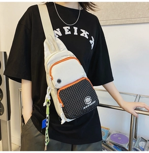 Detail view of water-resistant white canvas chest bag with orange zipper and black grid pocket