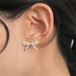 Detail of elegant pearl bow earrings featuring silver bead accent on the ear