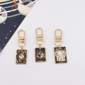 Three tarot card keychains with Magician and Lovers designs in gold-plated enamel finish