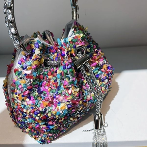 Detail of colorful rhinestone bucket bag featuring crystal handle and silver tassels
