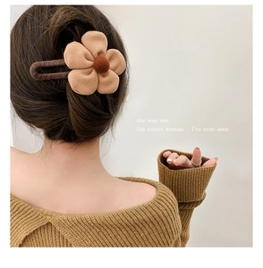 Close-up of a khaki plush flower hair claw clip securing a bun on a woman's head