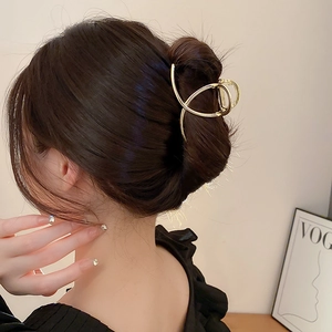 Golden irregular geometric metal hair claw clip shown in a stylish side-back view hairstyle