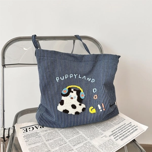 Detail of navy striped canvas tote bag featuring plush puppy embroidery and text