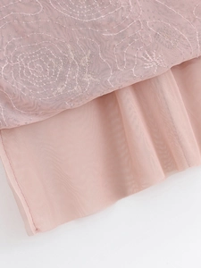 Detail shot of delicate floral embroidery on layered pink tulle fabric texture