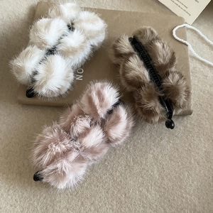 Détail de barrettes banane en fausse fourrure pelucheuse en beige, marron et rose