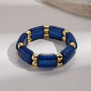 Macro detail of geometric deep blue resin beads and polished gold metal links on a bracelet