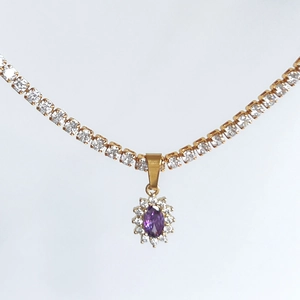 Macro detail of 18k gold plated tennis necklace with purple oval gemstone pendant