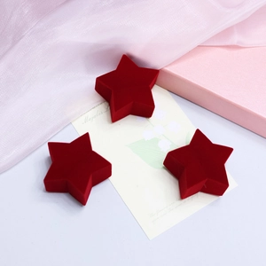 Three red star-shaped velvet jewelry boxes on an elegant decorative background
