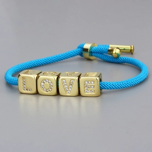 Detail des blauen geflochtenen Armbands mit goldenen LOVE-Blöcken und Kristallbesatz