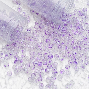 Macro shot of 8mm purple flower pattern glass beads spilling from clear tubes for DIY craft