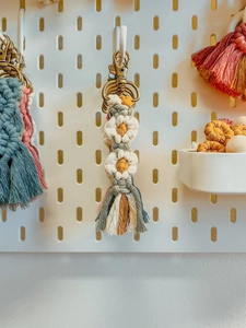 Gros plan de porte-clés fleurs tissés main avec fermoirs en métal sur un panneau blanc