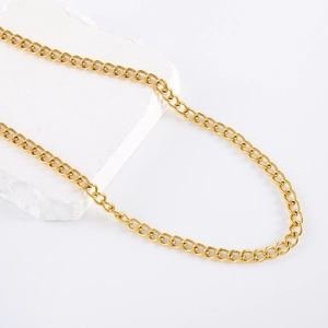 Close-up of a 6mm gold stainless steel chain necklace on a minimalist stone display