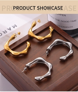 Irregular wavy C-shape earrings in gold and silver finish on a wooden display box