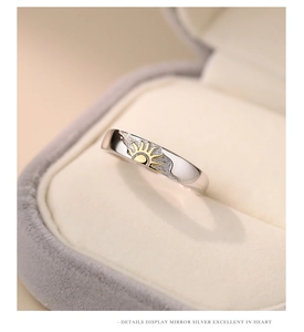Macro shot of polished silver ring featuring a golden sun relief in a jewelry box