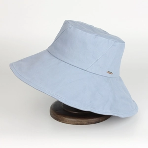 Detail of light blue wide brim cotton bucket hat with white stitching and metal logo