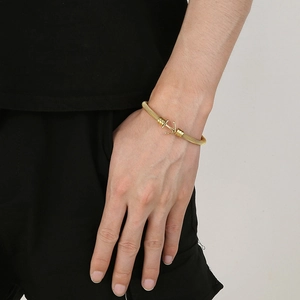 Golden woven wire stainless steel anchor cuff bracelet displayed on model's wrist