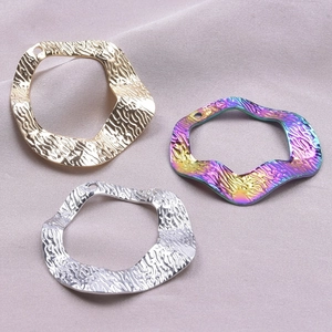 Macro view of textured wave metal pendants in gold, silver and rainbow plating