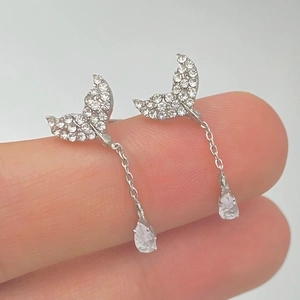 Close-up of silver mermaid tail earrings featuring sparkling crystals and pear-shaped drops