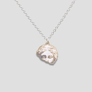 Detailed close-up of a silver Venus portrait pendant with white enamel and gold plating