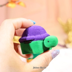 Detailed view of turtle-shaped jewelry box featuring soft purple flocking and green body