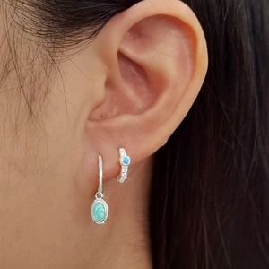 Detail view of 925 silver asymmetric earrings with turquoise and blue opal inlay on ear