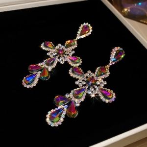 Detail shot of colorful cross drop earrings with sparkling gems on black velvet