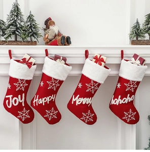 Detail view of four red knitted Christmas stockings with plush white cuffs on fireplace