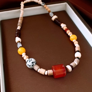 Detailed top view of a colorful beaded necklace with resin and wooden beads in a jewelry tray