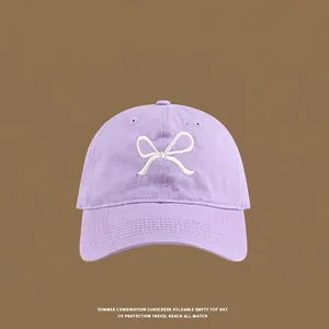 Detailed close-up of light purple cotton sun hat with white bow embroidery on front
