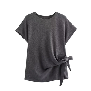 Detailed view of dark grey knit top featuring a stylish side tie knot at the hem