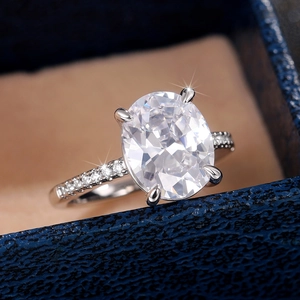 Macro shot of oval cut zirconia ring with side stones in a blue jewelry box