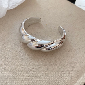 Detailed view of silver croissant twist bangle featuring irregular textured metal surface