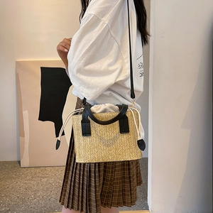 Fashionable straw woven crossbody bag with black leather handles and drawstring liner