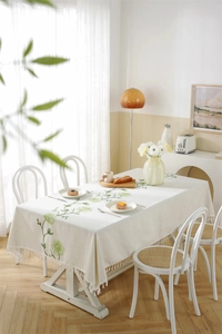 Close-up of geometric floral embroidery and fringe trim on beige waterproof tablecloth