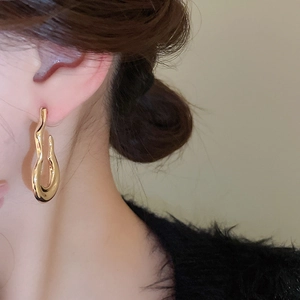 Close-up of golden irregular lava-style earring worn on model for minimalist fashion