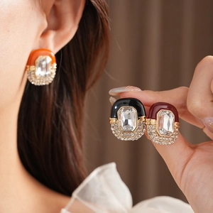 Detail shot of vintage oval earrings with crystal stones and colored enamel finish